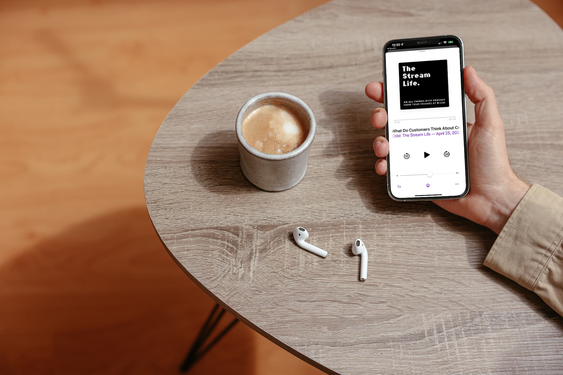mockuuups-simple-handheld-iphone-mockup-held-on-the-table-with-a-pair-of-airpods-at-the-side